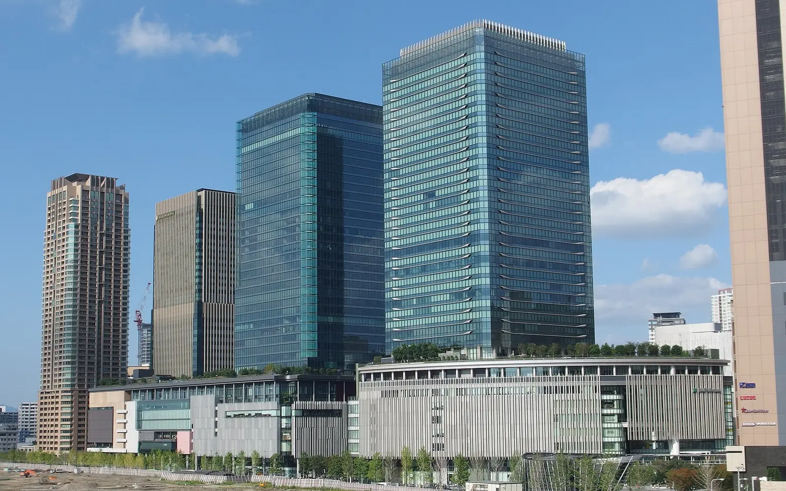 Glass office towers and the long retail podium of Grand Front Osaka in Umeda under a blue sky