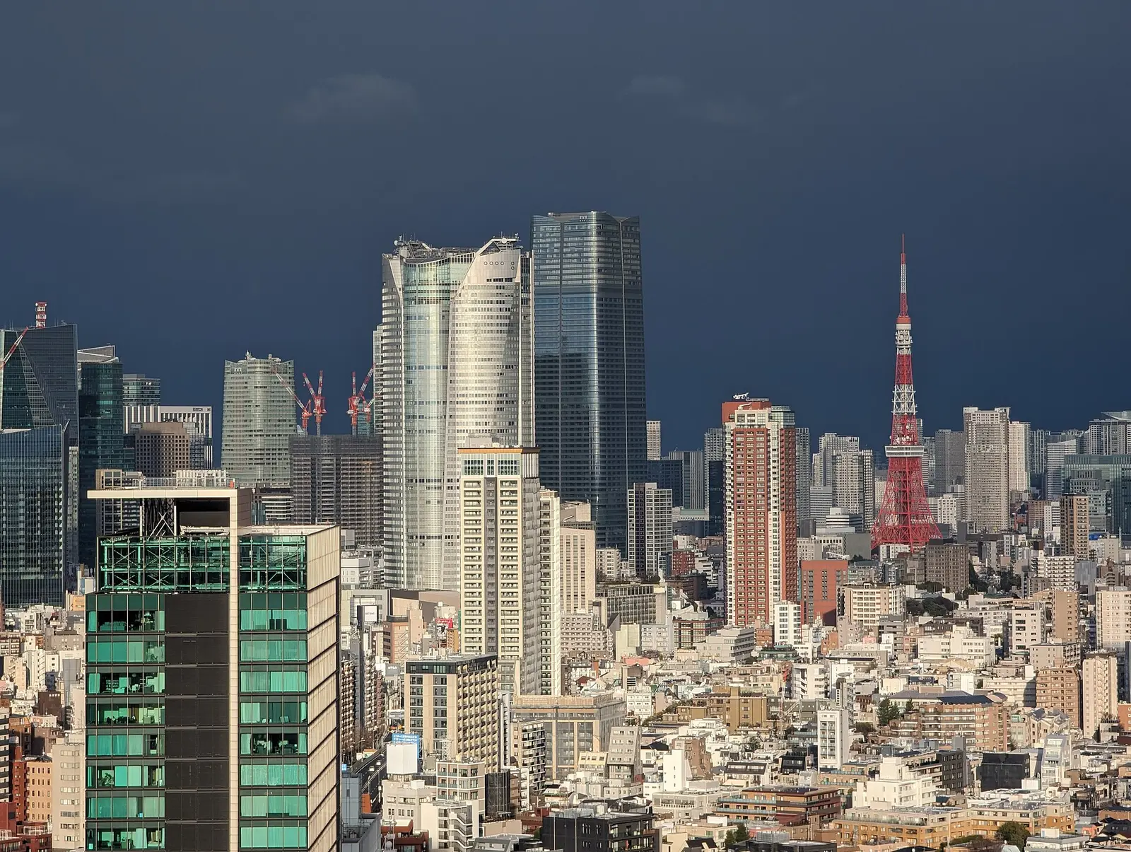 Roppongi Hills Mori Tower and Tokyo Tower under a dark stormy sky
