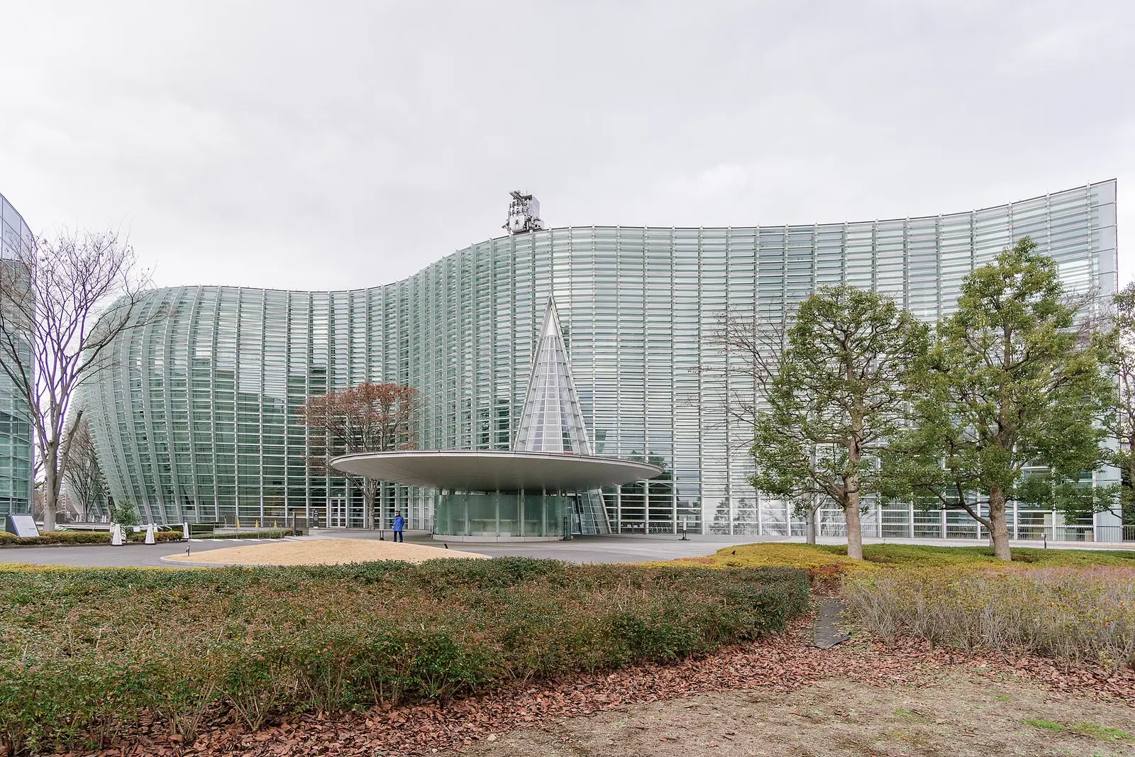 Curved glass facade of the National Art Center in Roppongi, Tokyo, with its cone shaped atrium and round entrance canopy