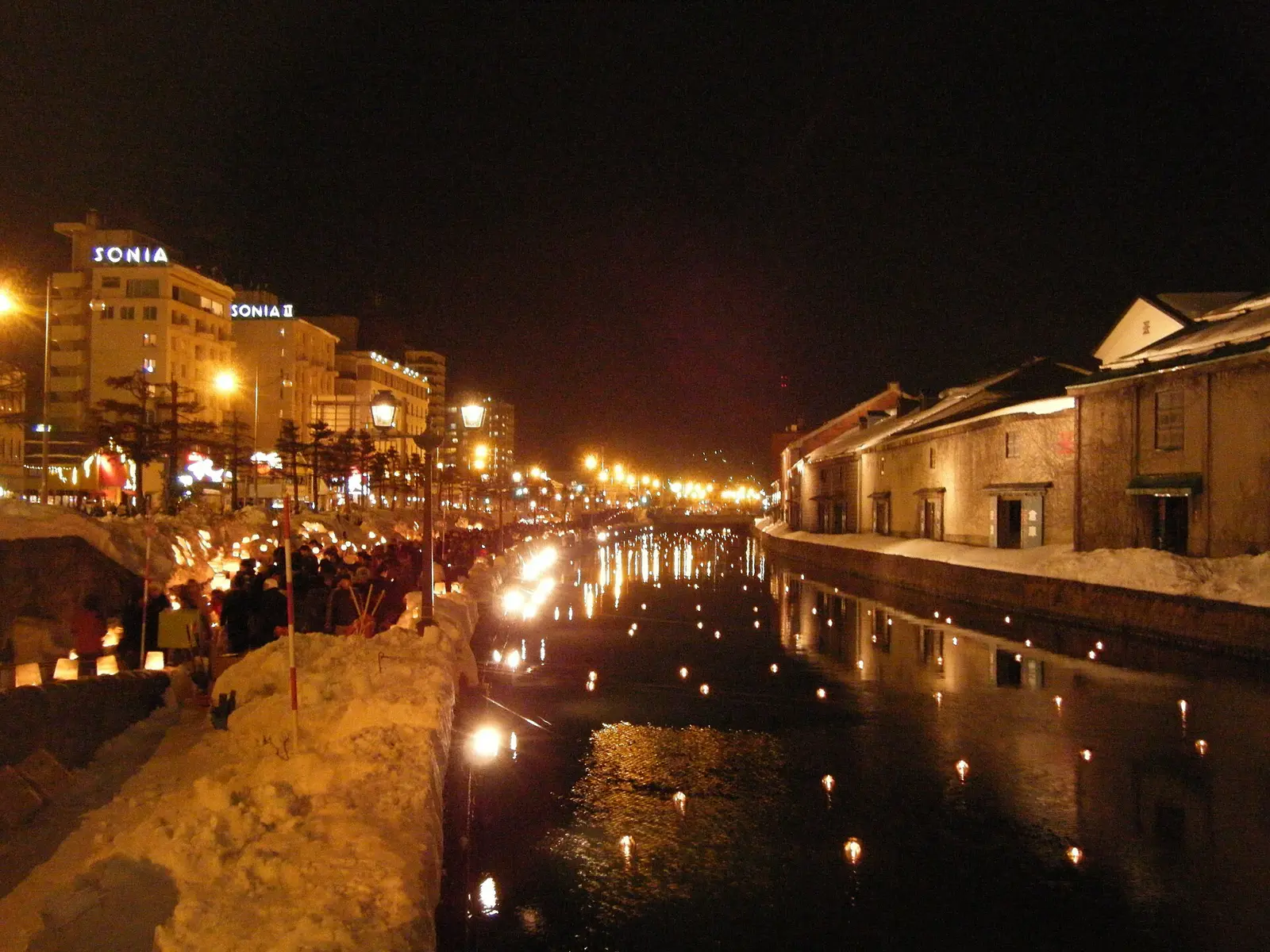 Candle lanterns in the snow beside Otaru Canal and its warehouses at night during the Snow Light Path