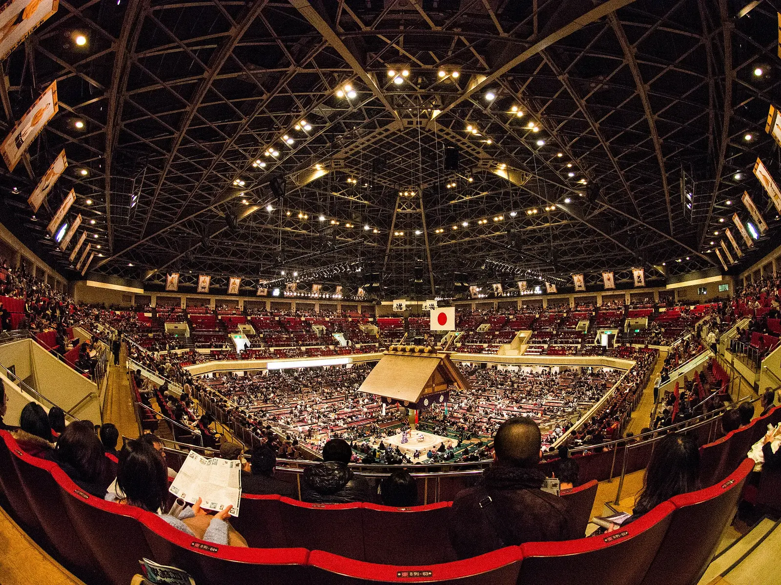 Crowd in the Ryogoku Kokugikan sumo hall under the suspended shrine roof at the January 2014 tournament
