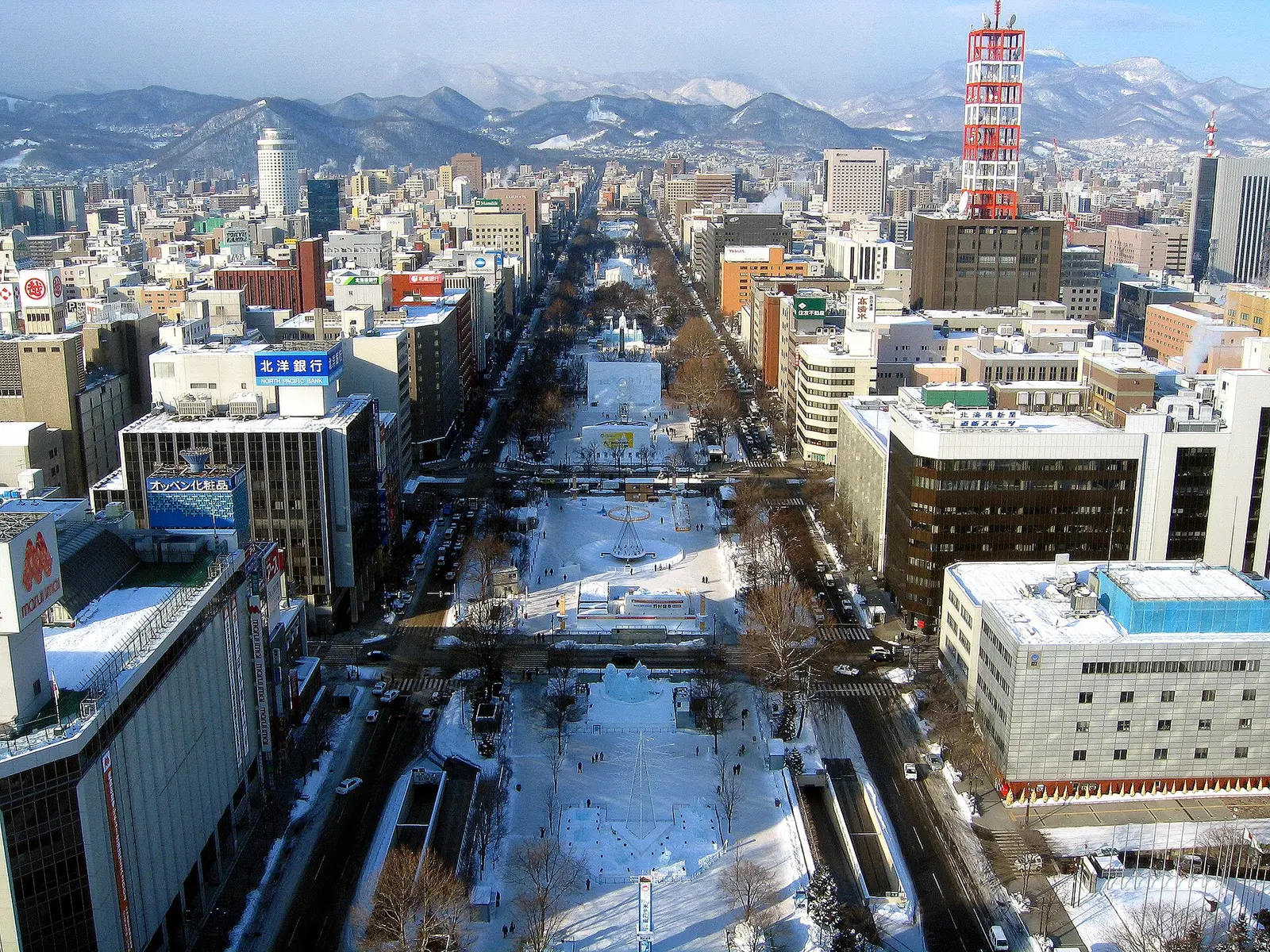 Aerial view of snow covered Odori Park running through downtown Sapporo with mountains behind