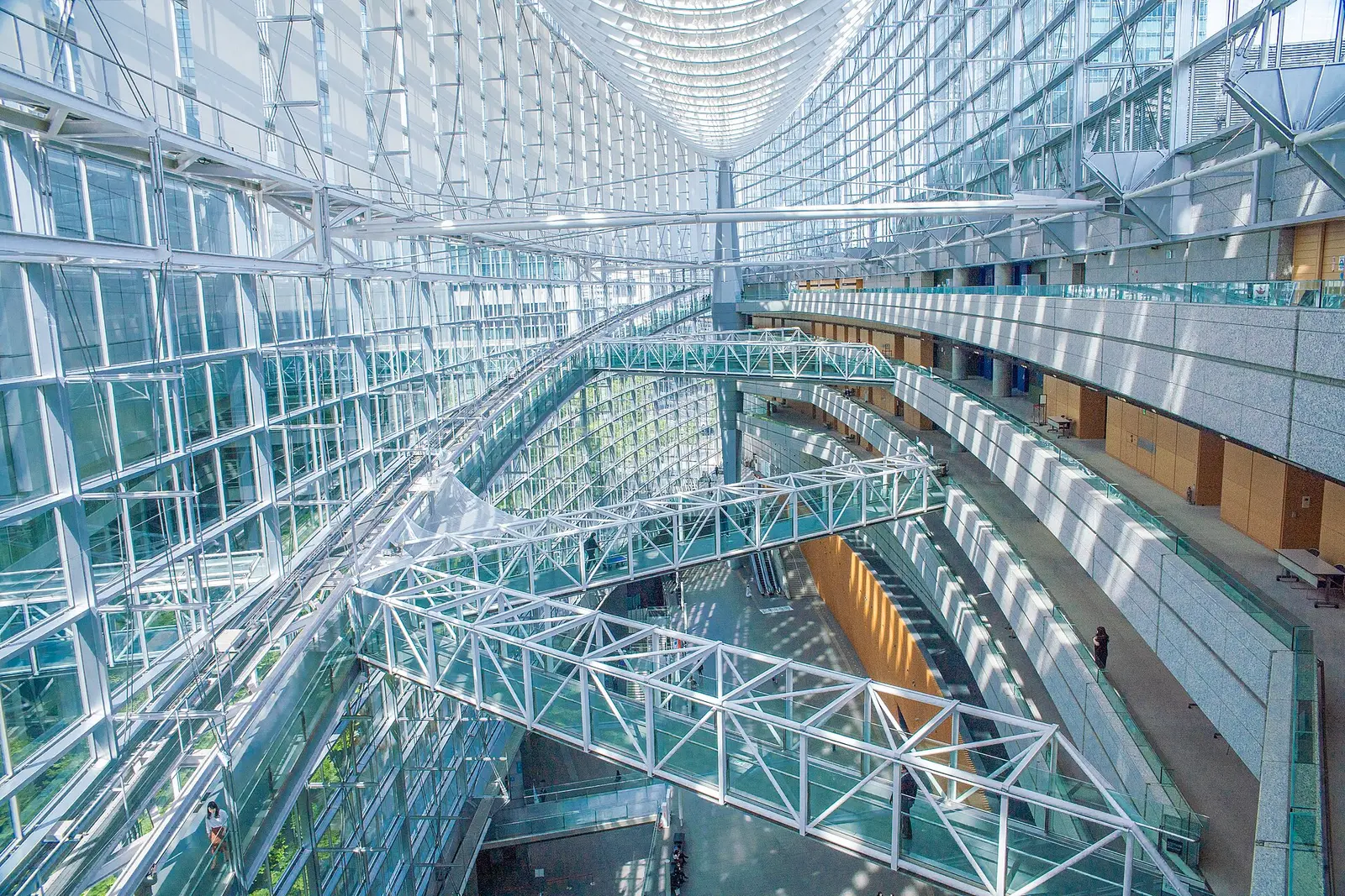 Glass atrium of the Tokyo International Forum with footbridges crossing the lobby void beneath a curved glass roof